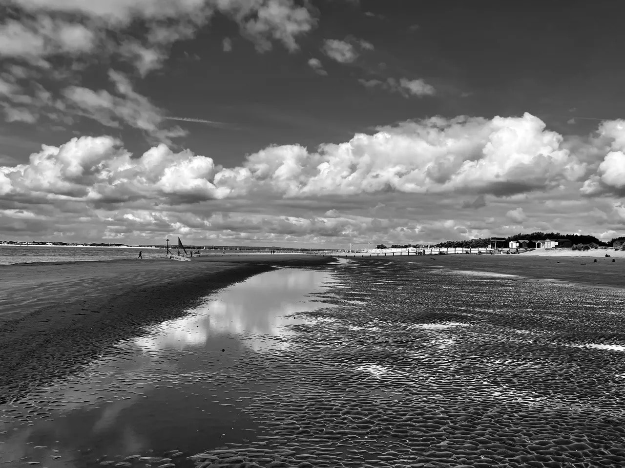Black and white beach landscape with dramatic clouds reflected in wet sand